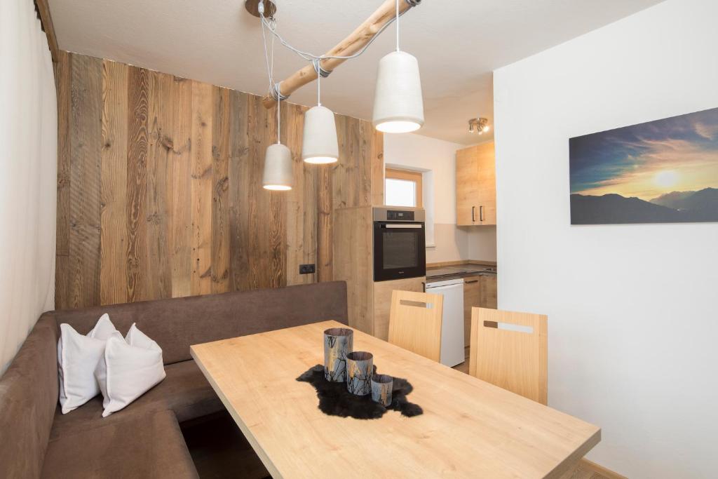 a dining room with a table and a kitchen at Angerer Alpine Suiten und Familienappartements Tirol in Reith im Alpbachtal