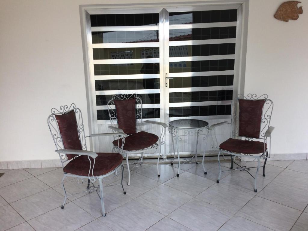 a glass table and four chairs and a window at Casa, Praia e Lazer. in Solemar