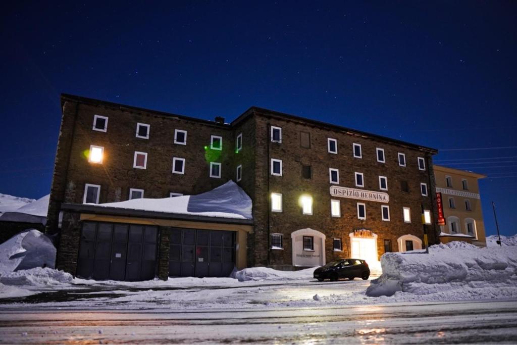 a building with a car parked in the snow at night at Hotel Bernina Hospiz in Berninahäuser