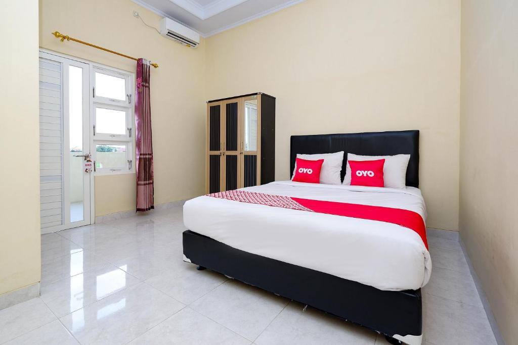 a bedroom with a large bed with red pillows at OYO 2058 Griya Ria in Solo