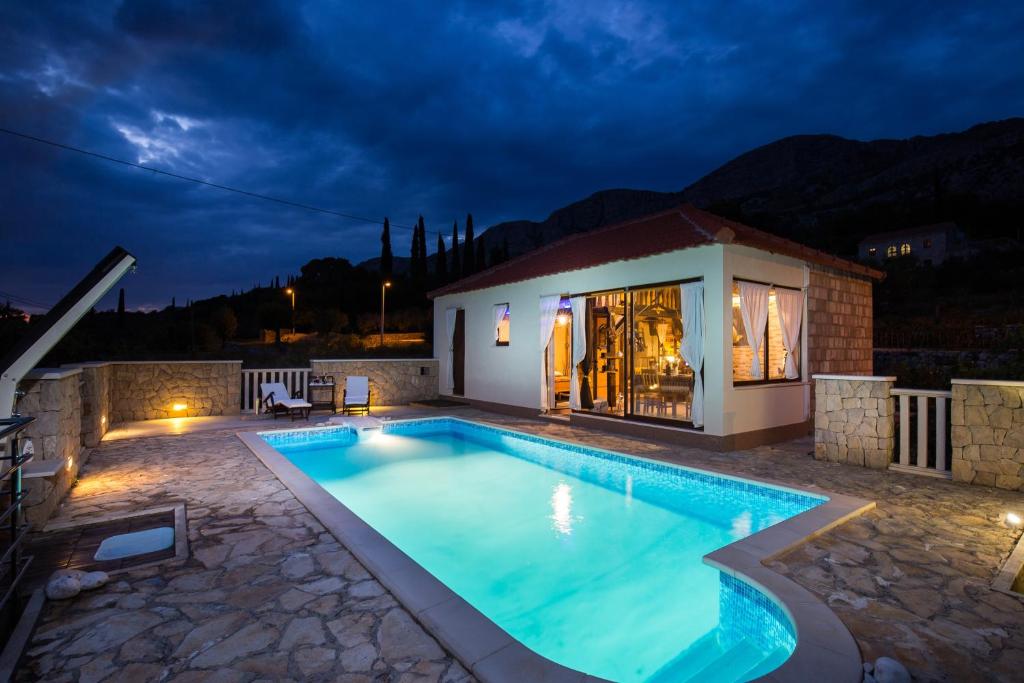 una piscina en un patio trasero por la noche en Holiday Home Lazuština Paradise, en Mihanići
