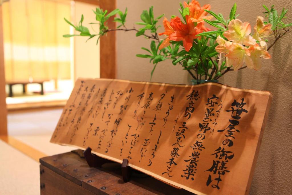 a sign on a table with a vase of flowers at Konashi No Yu Sasaya in Matsumoto