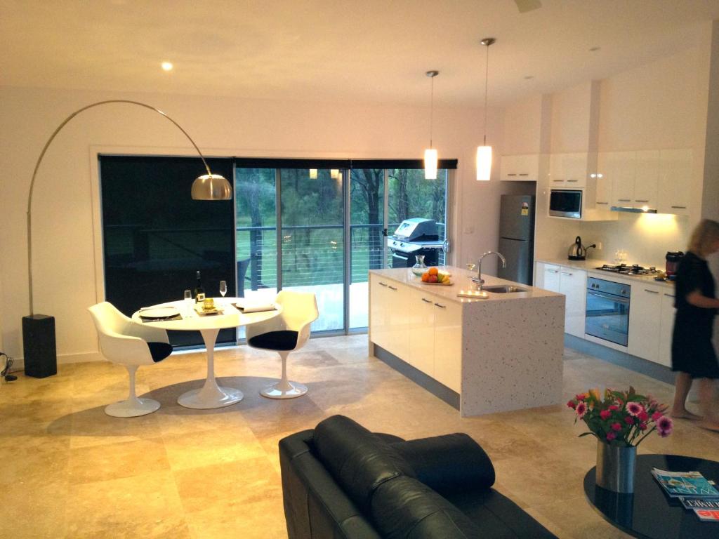 eine Küche und ein Wohnzimmer mit einem Tisch und einem Sofa in der Unterkunft Deja Vu Estate in Pokolbin