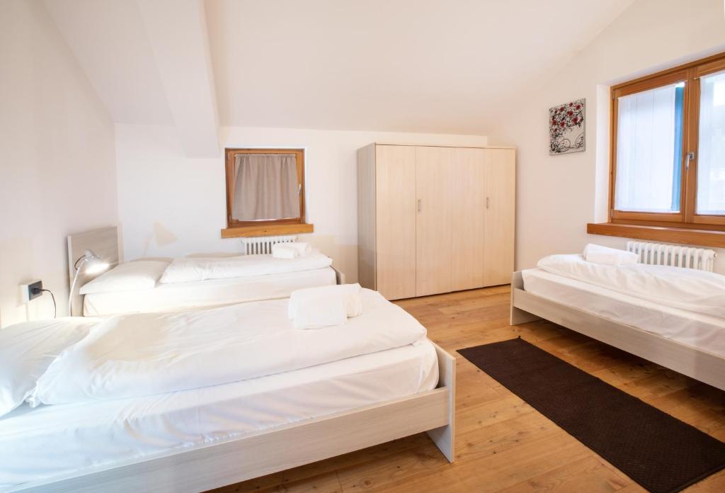 3 Betten in einem Zimmer mit weißen Wänden und Holzböden in der Unterkunft Dolomites Seasons in Alleghe