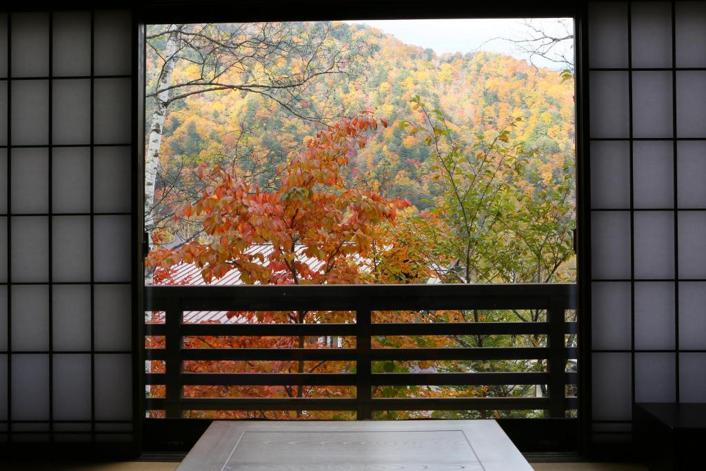 a window with a view of a forest at Konashi No Yu Sasaya in Matsumoto