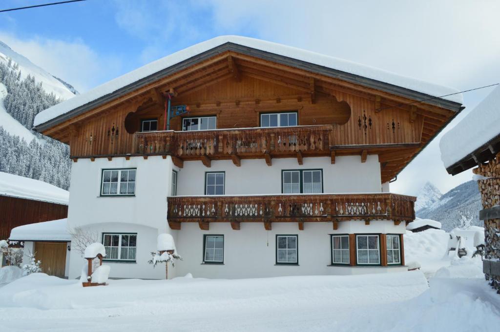 ein Haus mit einem Holzdach im Schnee in der Unterkunft Apart Lorenz in Häselgehr
