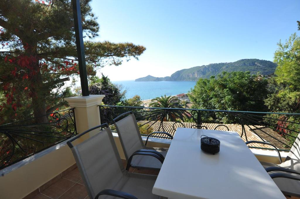 een witte tafel en stoelen op een balkon met uitzicht op de oceaan bij Villa Theodora View Apartments Eleni in Agios Georgios Pagon