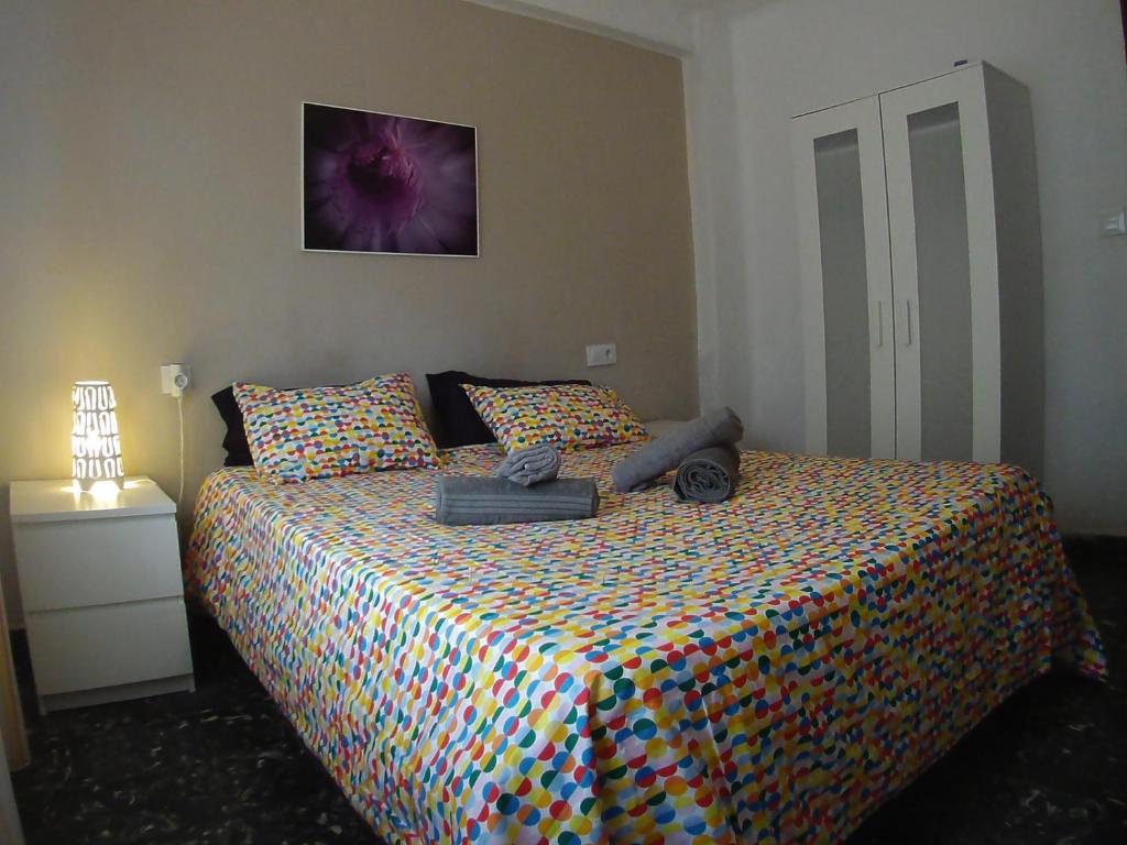 a bedroom with a bed with a colorful comforter at La casita de Pepe - piso compartido in Valencia
