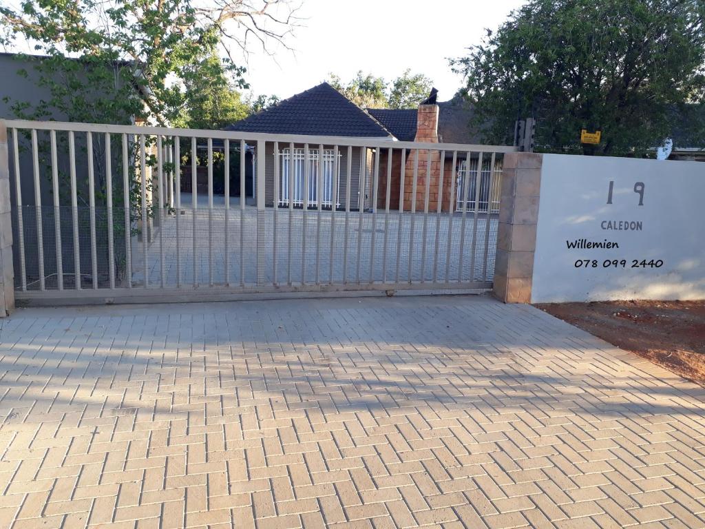 una recinzione bianca con un cancello di fronte a una casa di Caledon Overnight Rooms a Kimberley
