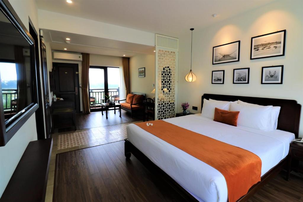 a bedroom with a large bed and a living room at Roxana River Villa in Hoi An