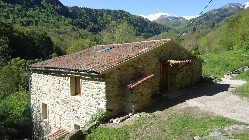 a stone house in a mountain with mountains in the background at Gîtes Le Paradoxe des Pyrénées in Montferrier