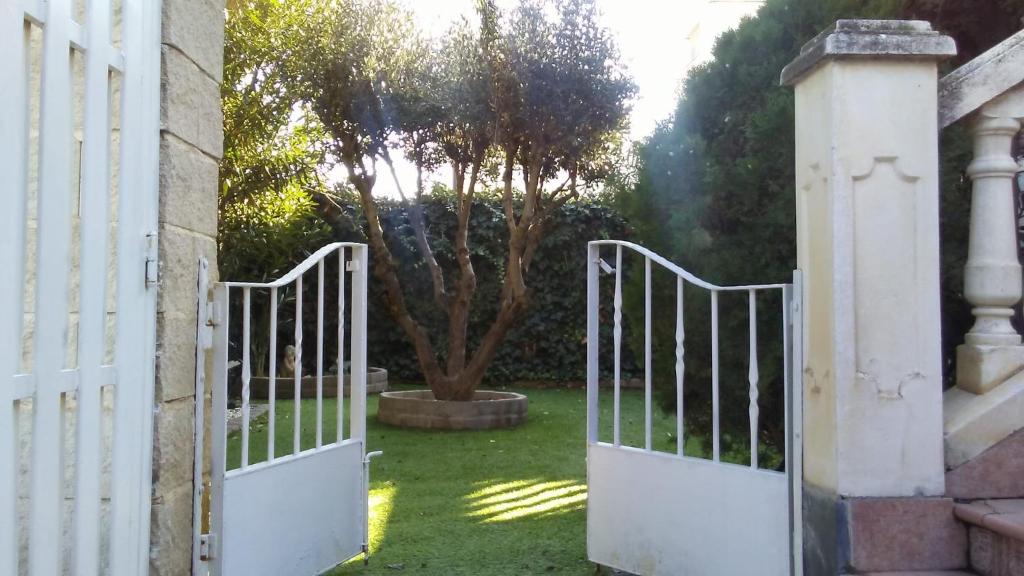 un cancello bianco in un cortile con un albero di Bodega íntima a Saragozza