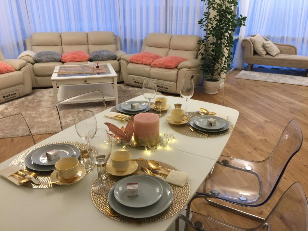a living room with a table with plates and wine glasses at Snieguolės apartamentai in Palanga