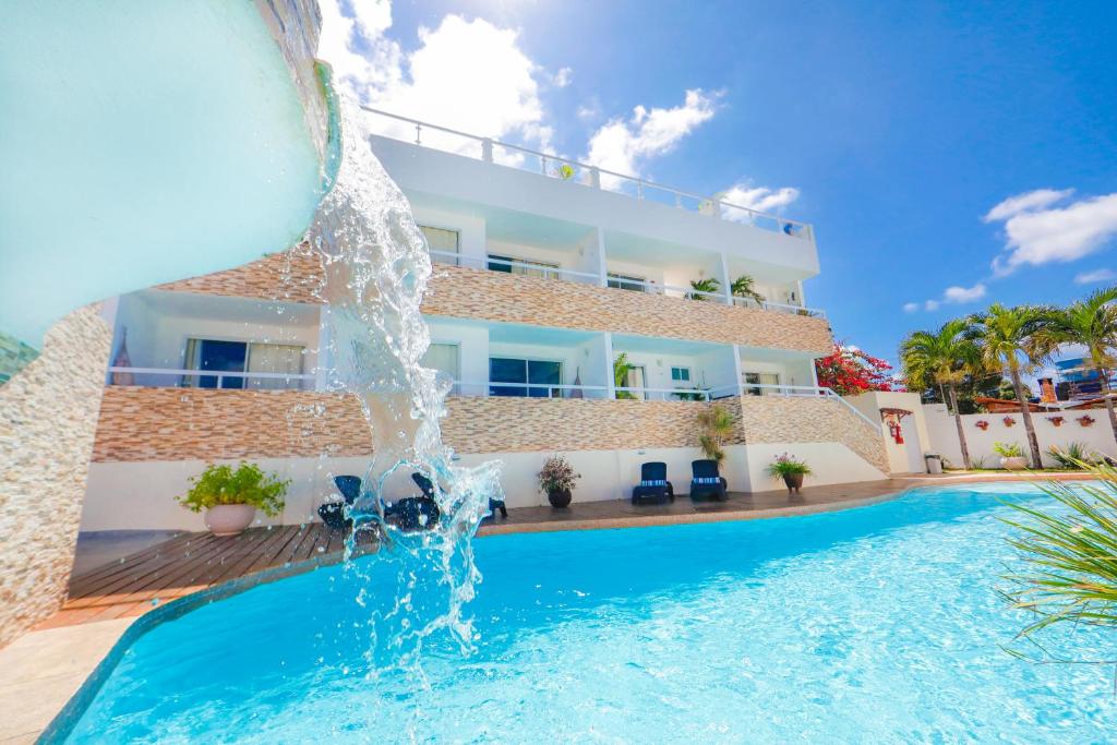 a pool with a water fountain in front of a hotel at Pipa Centro Residence in Pipa