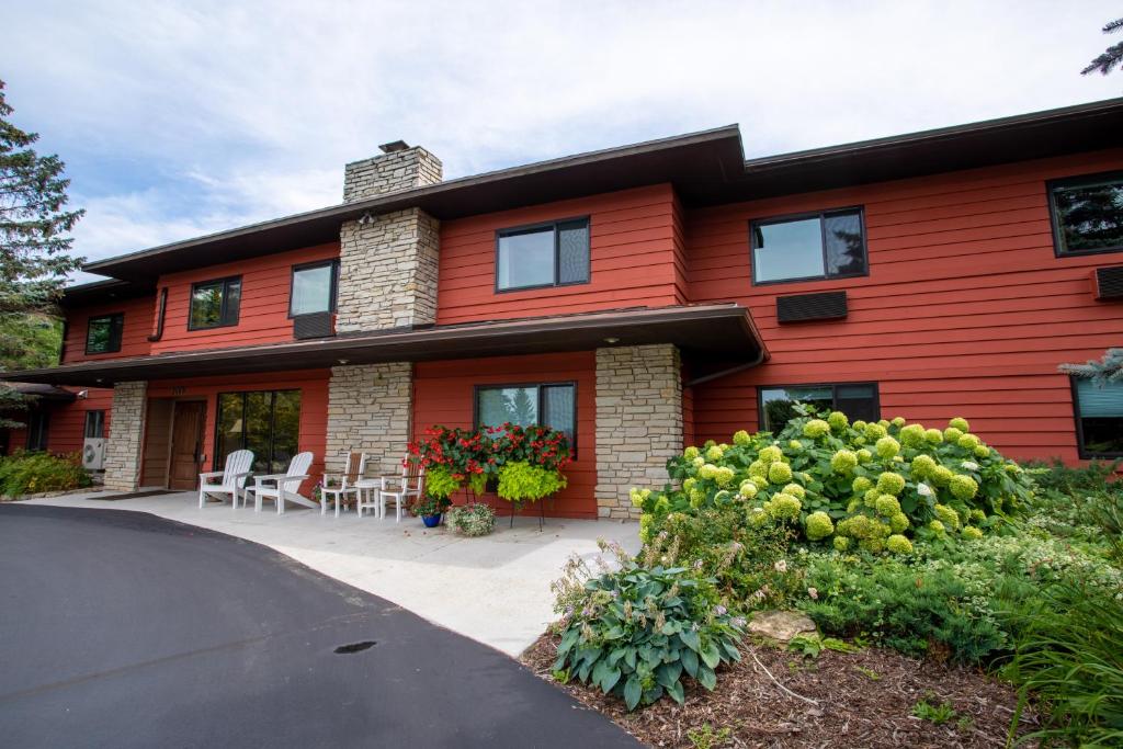 une maison rouge avec une terrasse et des chaises en face de celle-ci dans l'établissement Open Hearth Lodge, à Sister Bay