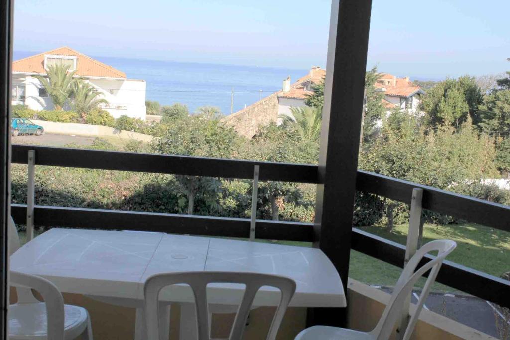 een witte tafel en stoelen op een balkon met uitzicht op de oceaan bij Anglet face à l'océan in Anglet