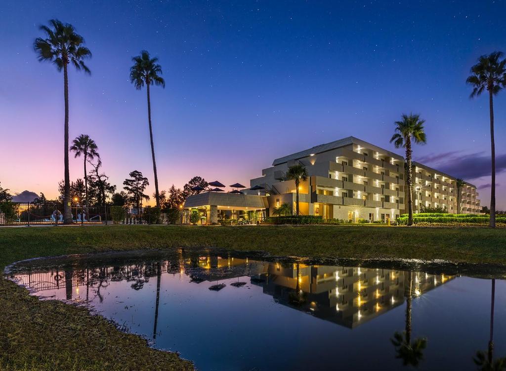 a building with palm trees in front of a pond at Palazzo Lakeside Hotel in Kissimmee