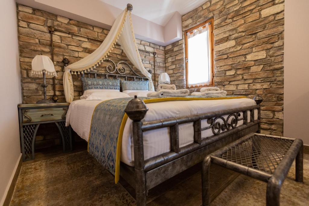 een slaapkamer met een bed en een stenen muur bij Maria's Boutique Rooms in Kórinthos