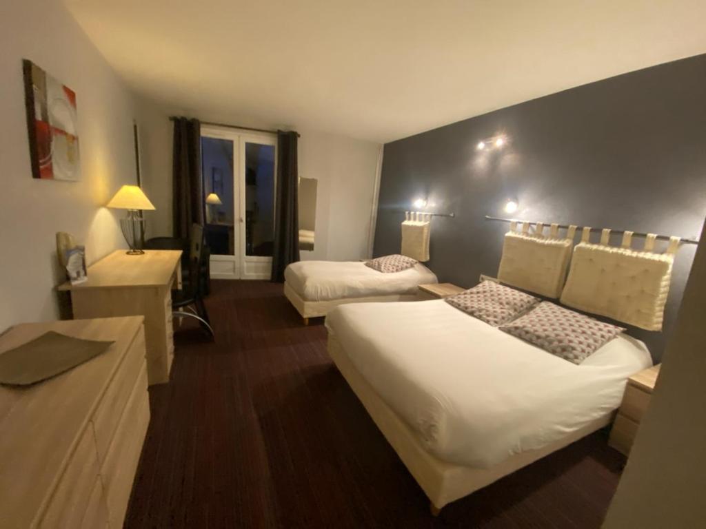 a hotel room with two beds and a desk at Hôtel des Chazes in Saint-Jacques-des-Blats