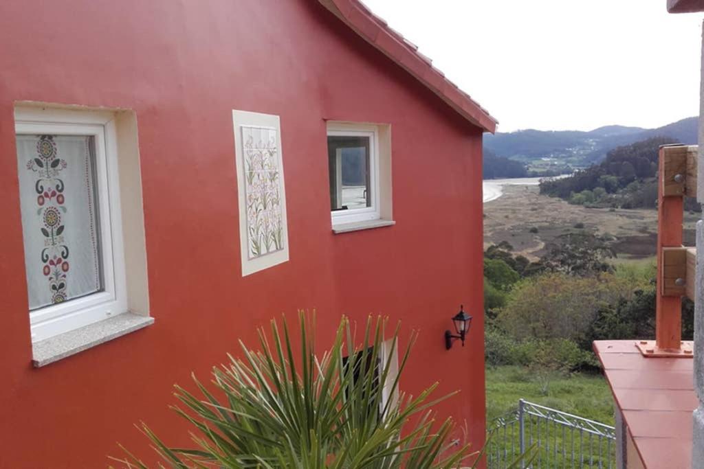 een rood huis met twee ramen aan de zijkant bij Casa acogedora con vistas al mar in Valdoviño