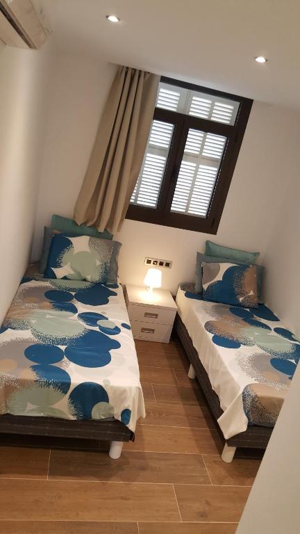 two beds in a room with two windows at Pinien Platz in Cala Ratjada