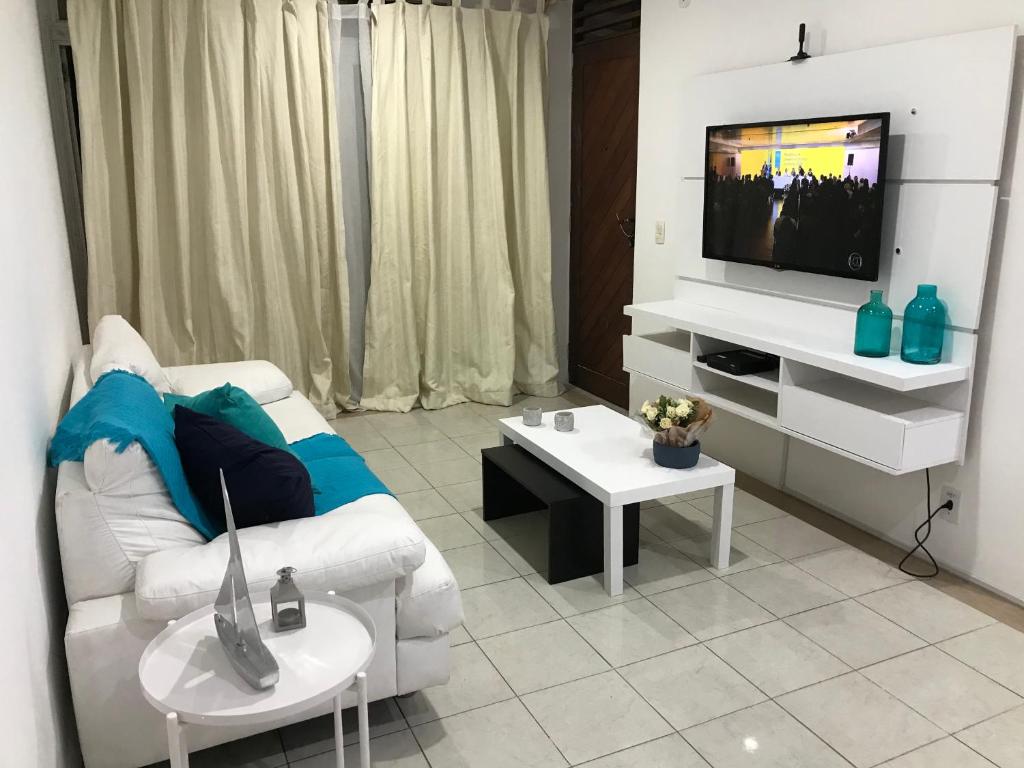 a living room with a white couch and a tv at Apt localização excelente in Maceió