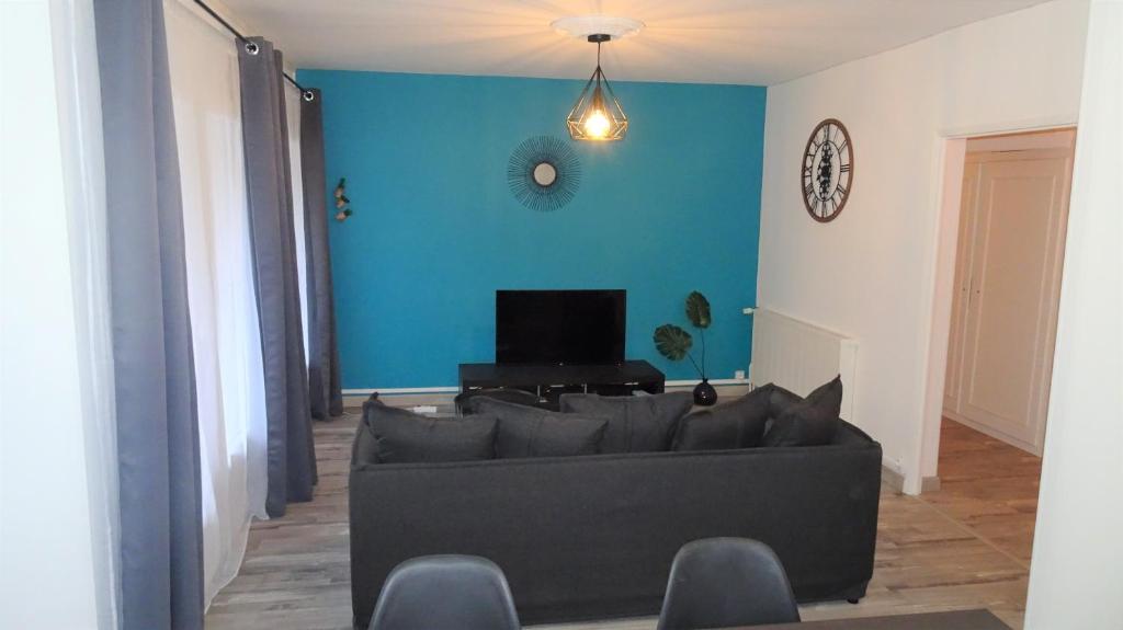 a living room with a couch and a blue wall at Grand appartement T3/T4 proche des berges du Cher in Montluçon