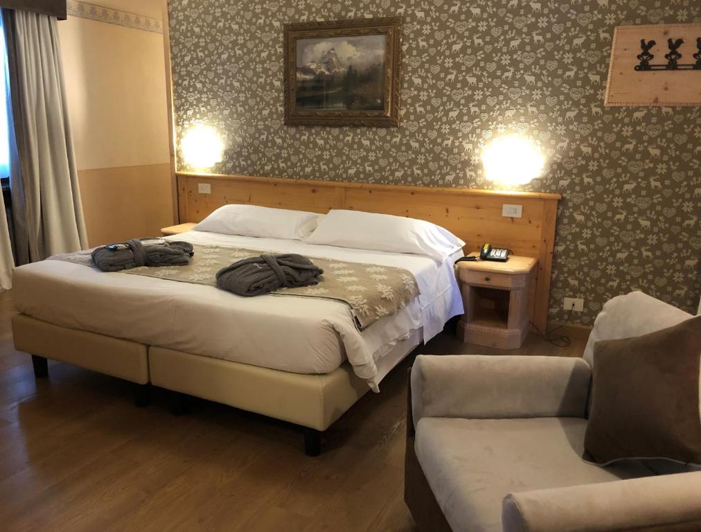 sypialnia z łóżkiem, krzesłem i kanapą w obiekcie Hotel Edelweiss 3 Stelle SUPERIOR w mieście Breuil-Cervinia