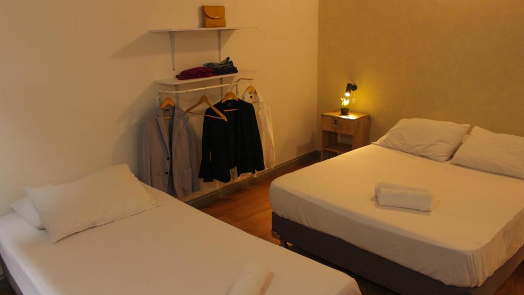 a bedroom with two beds and a closet with a robe at La Vaina Cali in Cali