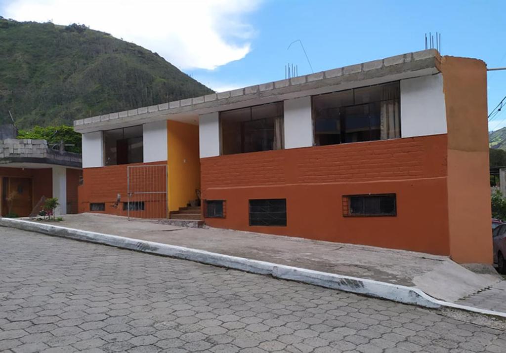 ein orangefarbenes und weißes Gebäude mit einer Kopfsteinpflasterstraße in der Unterkunft Casa Vacacional en Baños de Agua Santa in Baños