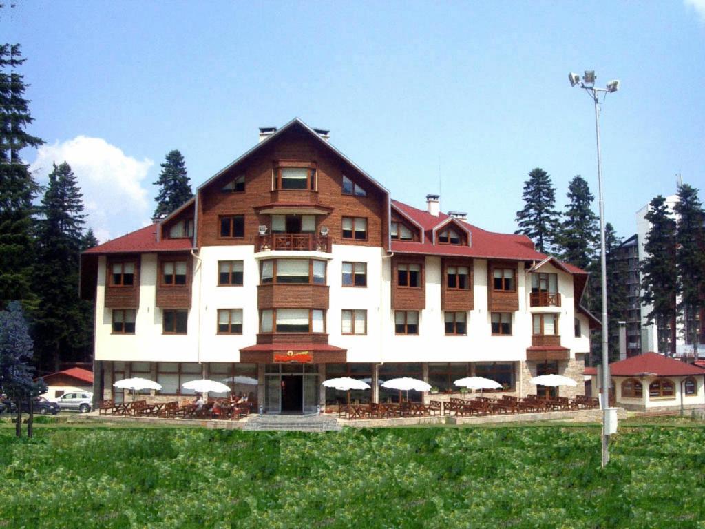 a large building with tables and umbrellas in front of it at Ice Angels Hotel in Borovets