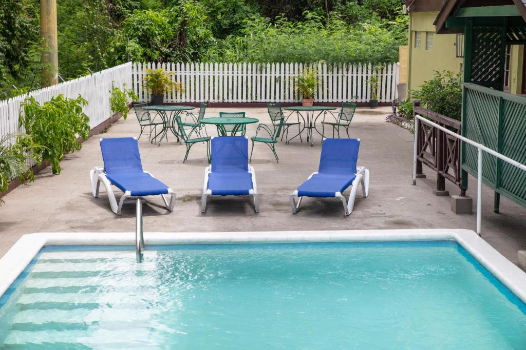 uma piscina com cadeiras e uma mesa e uma mesa e cadeiras em Pineapple Court Hotel em Ocho Rios