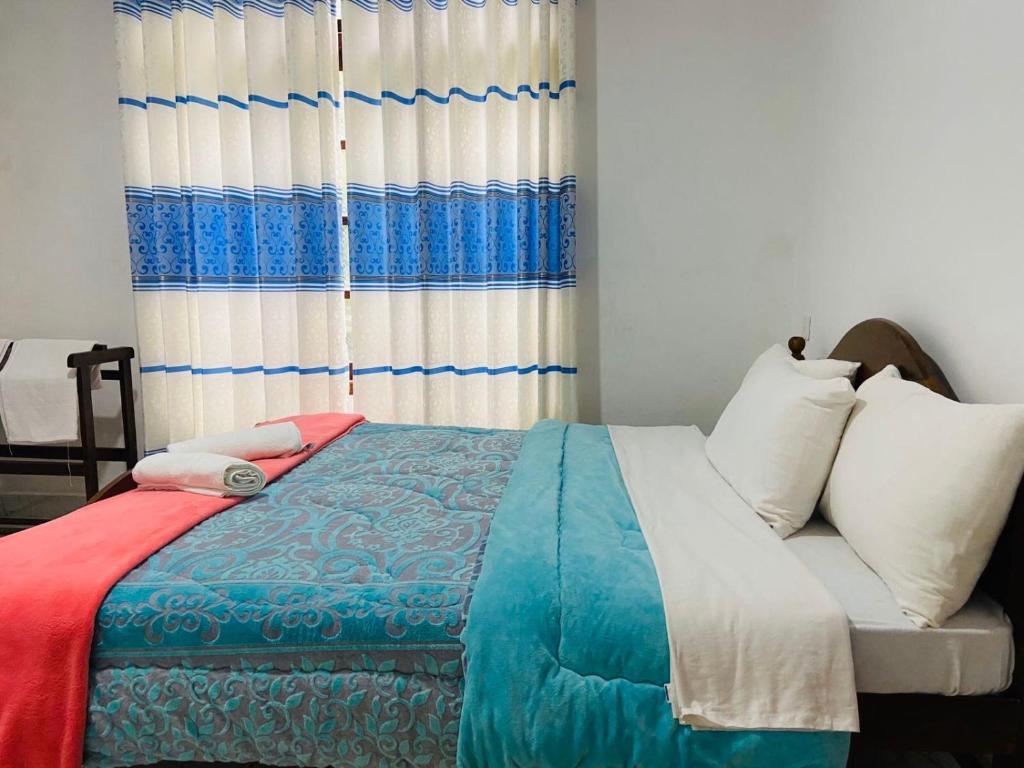 1 dormitorio con 1 cama con manta azul y blanca en Shiny View en Nuwara Eliya