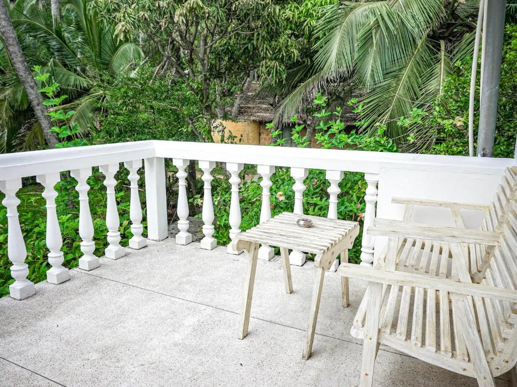 a white railing with a table and a chair on a porch at Nuga Eden Tangalle in Tangalle