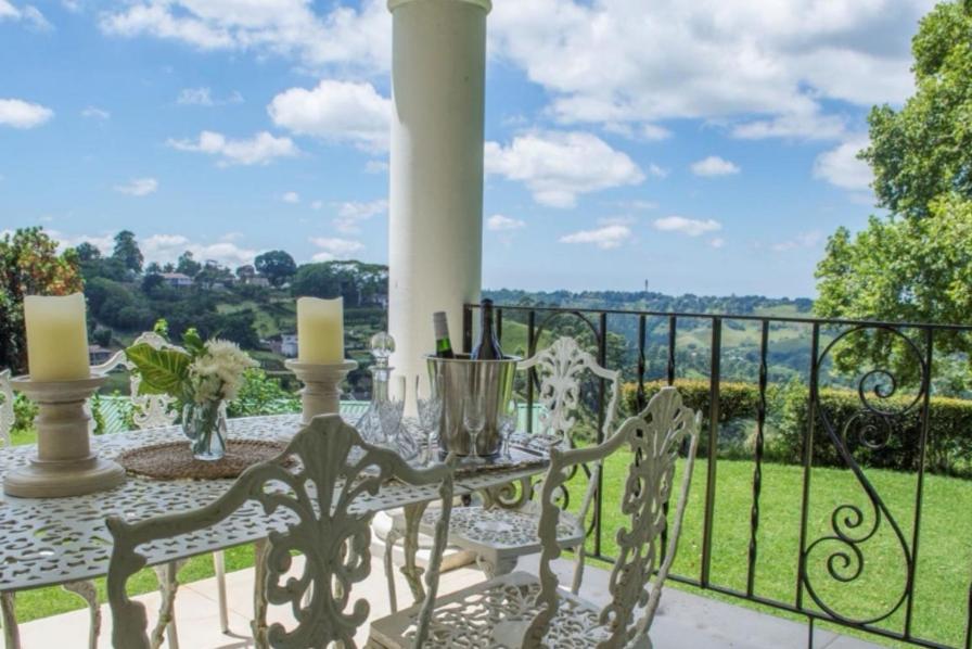 un balcón con una mesa con botellas de vino y velas en Churchill House, en Hillcrest