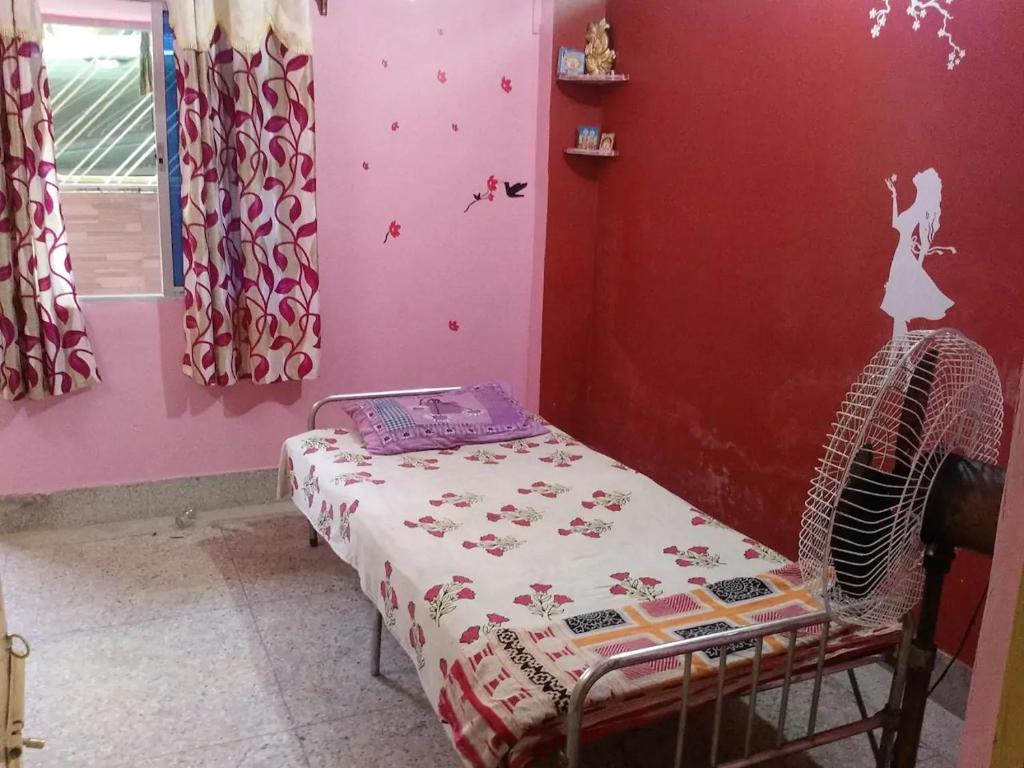 een slaapkamer met een bed in een rode muur bij Pushpa Di Ghar in Calcutta