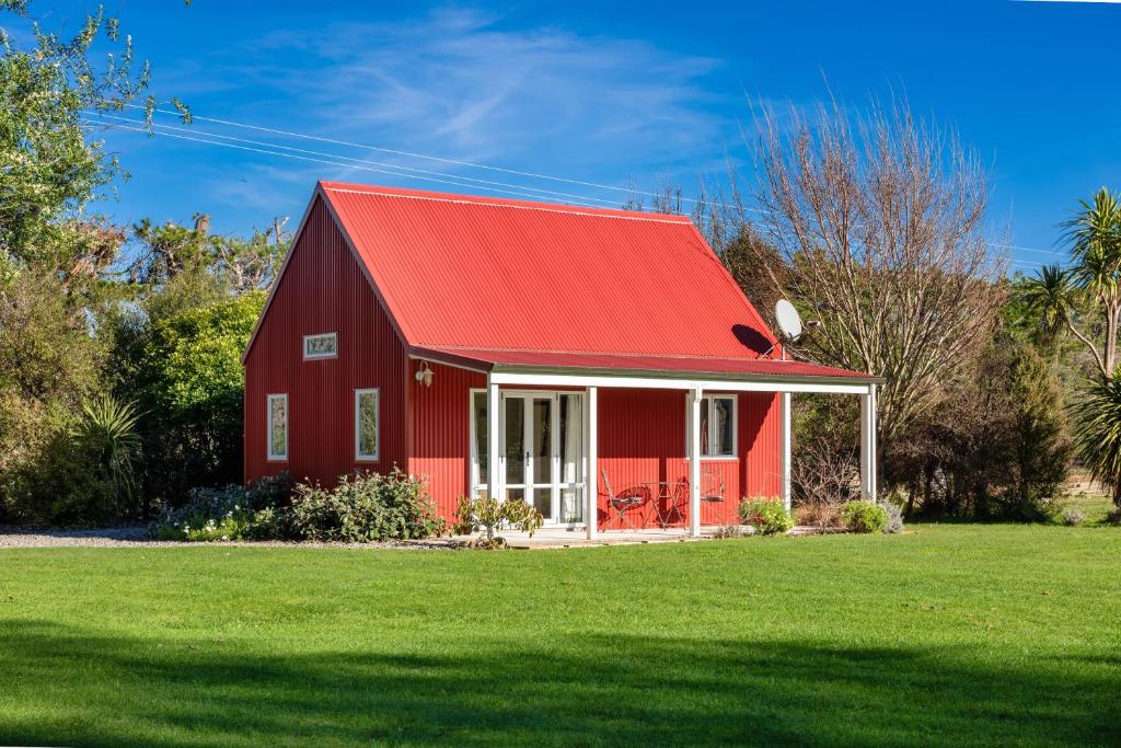 a red barn with a red roof on a green field at Brookhaven Cottage in Renwick