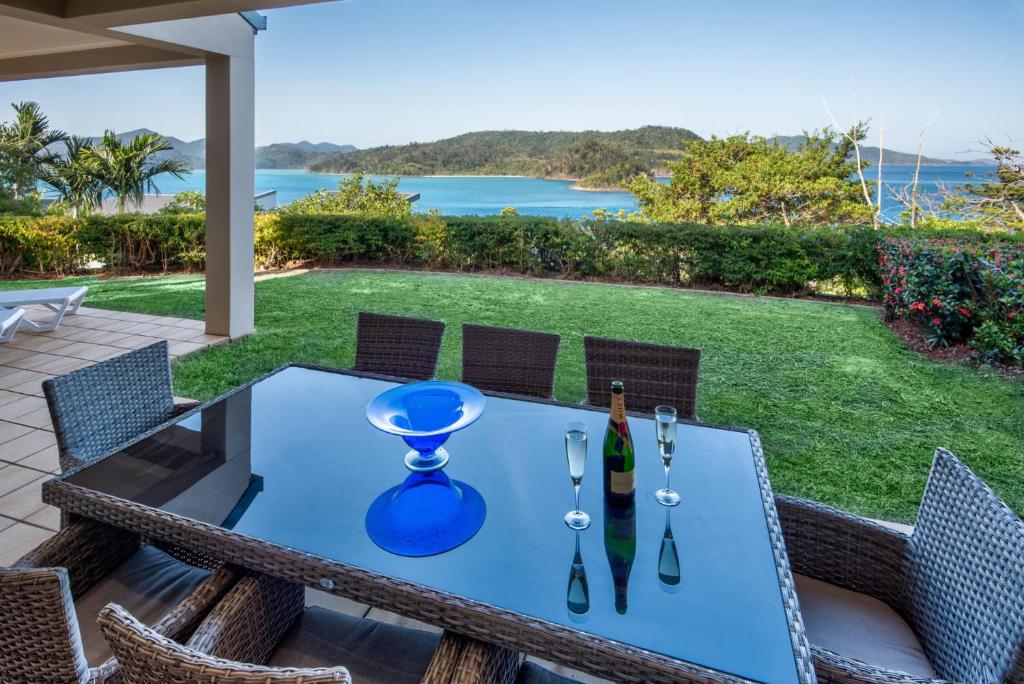 einen Tisch mit einer Flasche Wein auf einer Terrasse in der Unterkunft La Bella Waters 1 Wide Reaching Ocean Views And Buggy in Hamilton Island