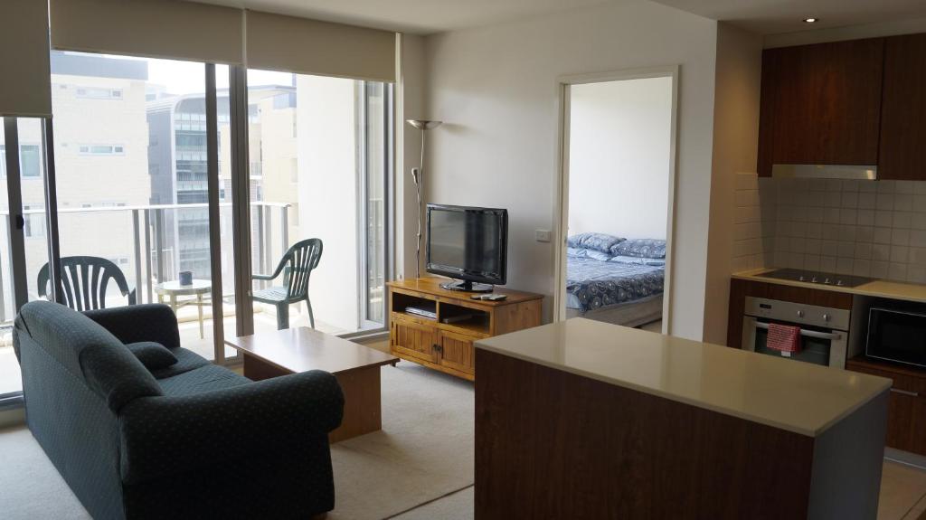 a living room with a television and a kitchen with a bed at Metropolitan in Canberra