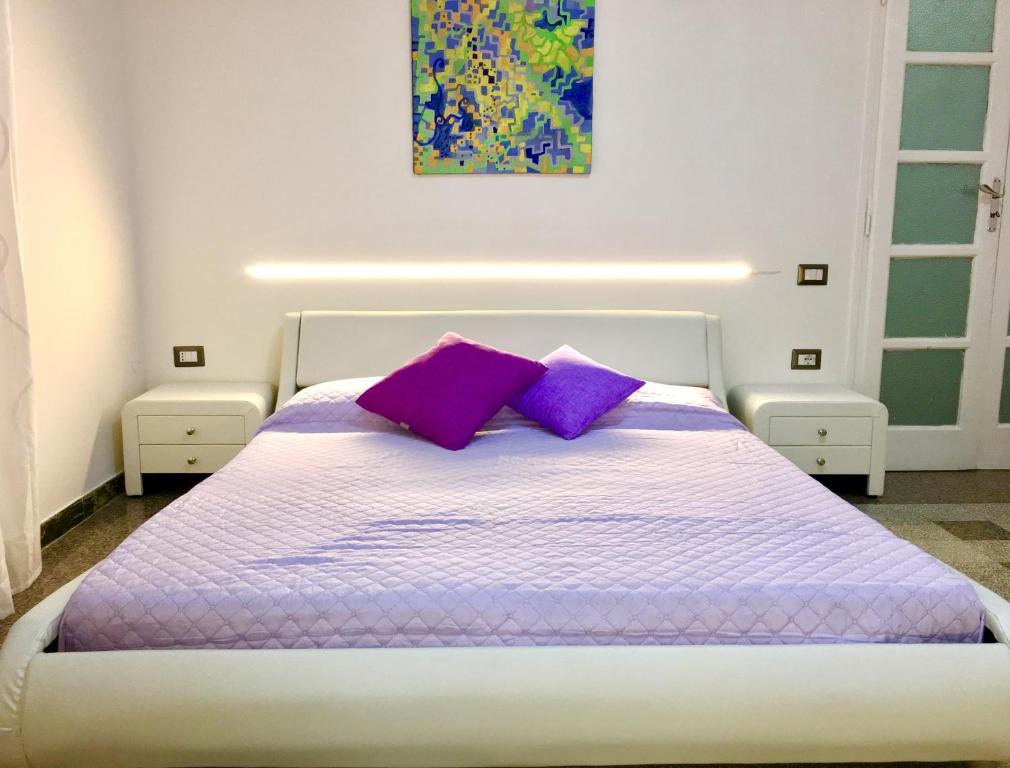 1 dormitorio con cama blanca y almohadas moradas en Camera matrimoniale privata in appartamento condivisibile en Salerno