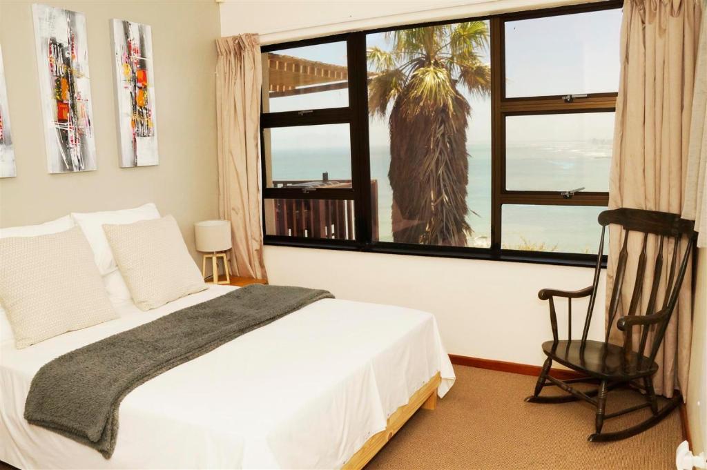 1 dormitorio con cama y ventana grande en Palm Tree Self-Catering Apartment en Gordonʼs Bay