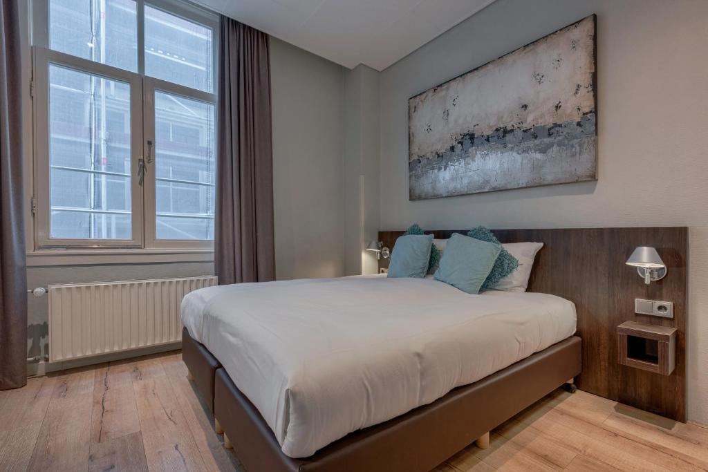 a bedroom with a bed and a large window at Hotel Damsquare in Amsterdam