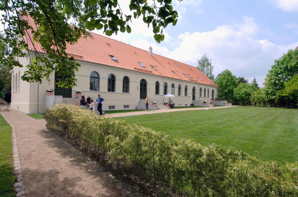 ein Gebäude mit einem großen grünen Feld davor in der Unterkunft Kavaliershaus Schloß Blücher am Finckenersee in Fincken