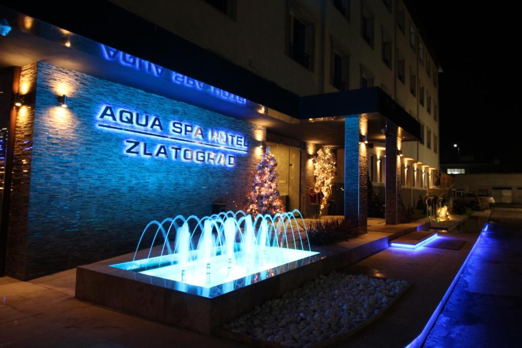 Aqua Spa Hotel Zlatograd في زلاتوغراد: نافورة امام مبنى به شجرة عيد الميلاد