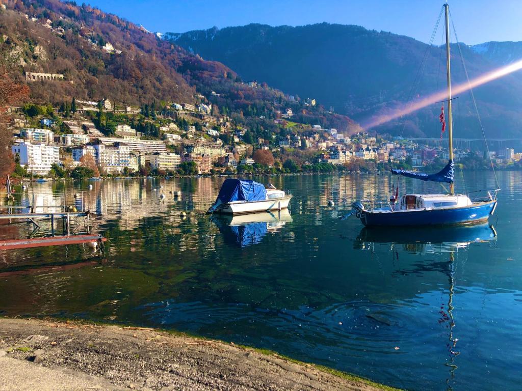 Due barche sono ormeggiate su un lago con una città di B&B Guest House Du Lac a Montreux