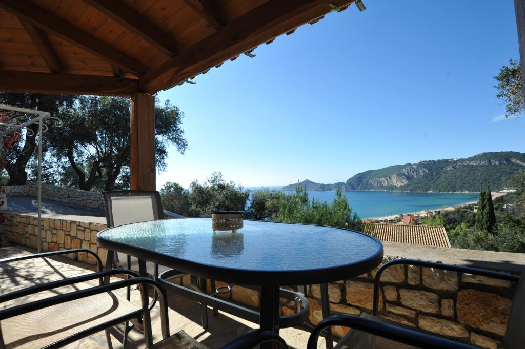 a table on a balcony with a view of a lake at Villa Theodora View Apartments Zeys in Agios Georgios Pagon