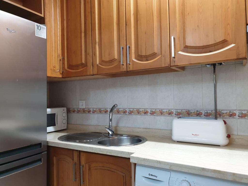 una cocina con armarios de madera y fregadero en Millan Astray, en Ceuta