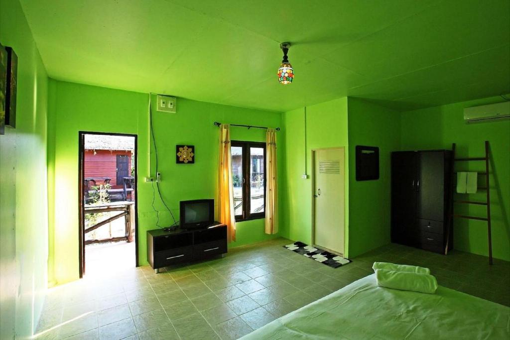 a green room with a bed and a television at PP Red Tuna Hut in Phi Phi Don