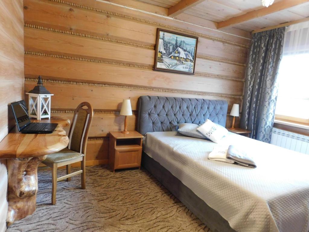 a bedroom with a bed and a table and a desk at Pokoje Goscinne Monika II in Zakopane