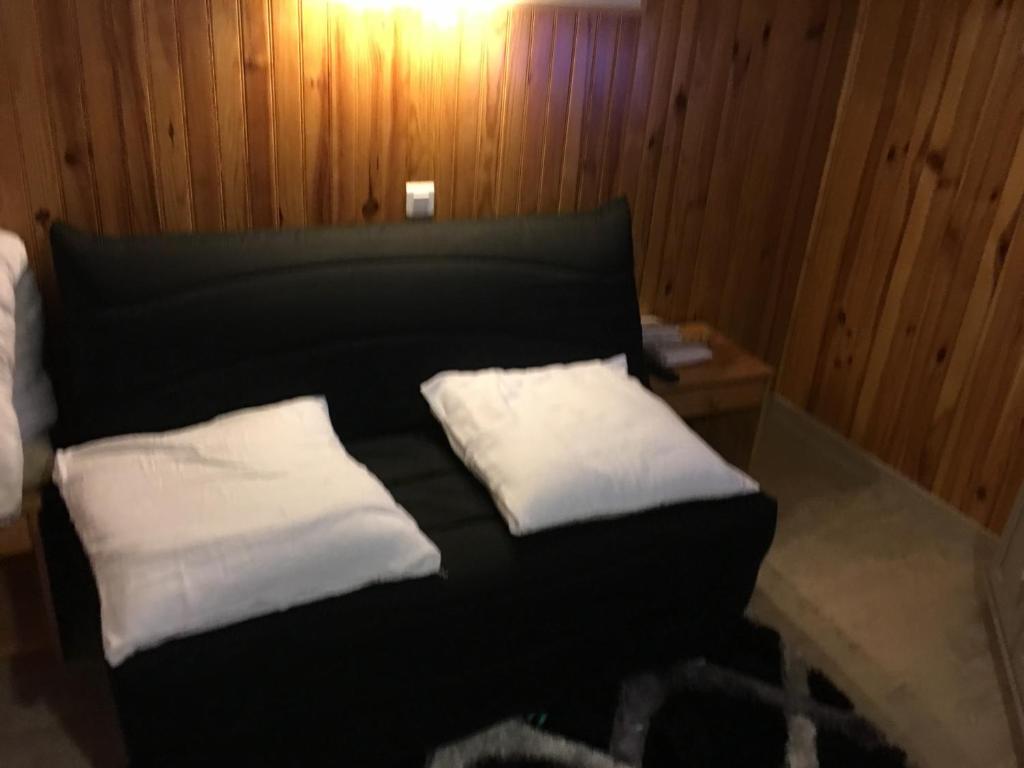 a black bed with two white pillows on it at Charmant studio in La Bresse